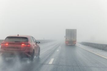 Weather-related vehicle accident - car and truck on a foggy highway.