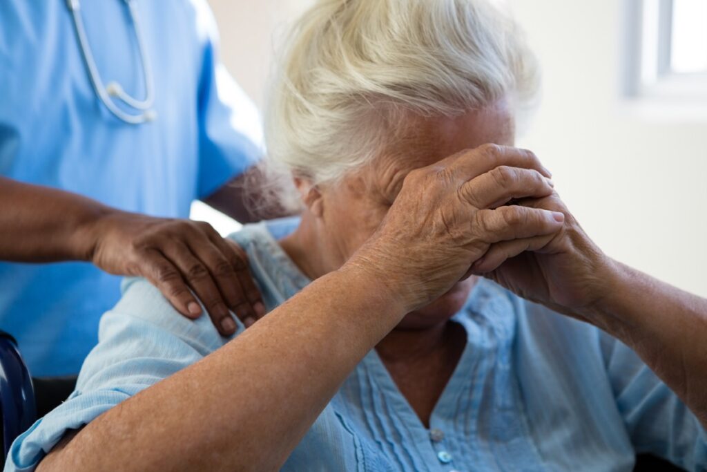 Woman with hands over her face in nursing home.