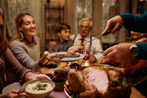 Close up of man serving turkey meat during Thanksgiving dinner at home.