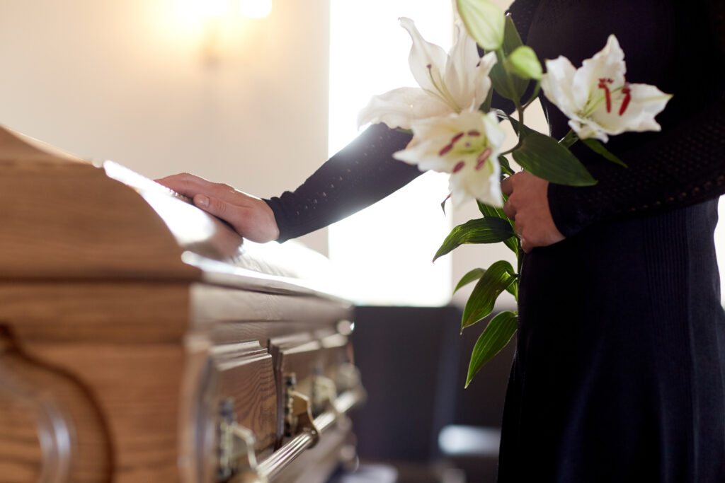 woman with white lily flowers and coffin at funeral in church - Paducah wrongful death attorneys Saladino & Schaaf