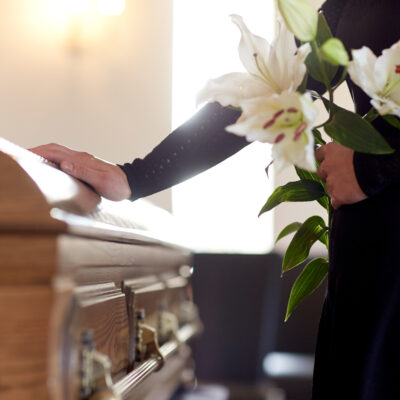 woman with white lily flowers and coffin at funeral in church - Paducah wrongful death attorneys Saladino & Schaaf