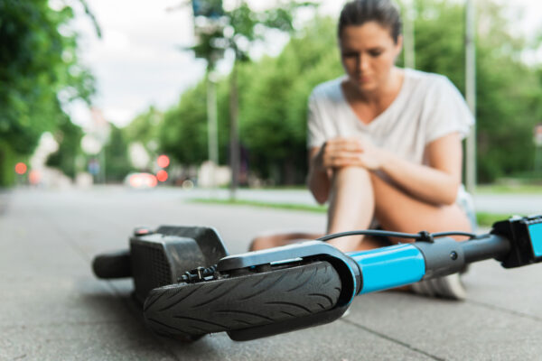 Woman lying in road after falling crashing on e-scooter - Call personal injury attorneys Saladino and Schaaf