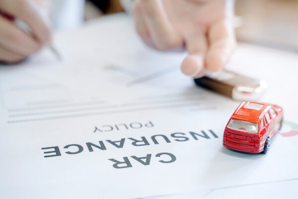 Car insurance policy with red car toy and blur image of man hand for vehicle insurance policy concept